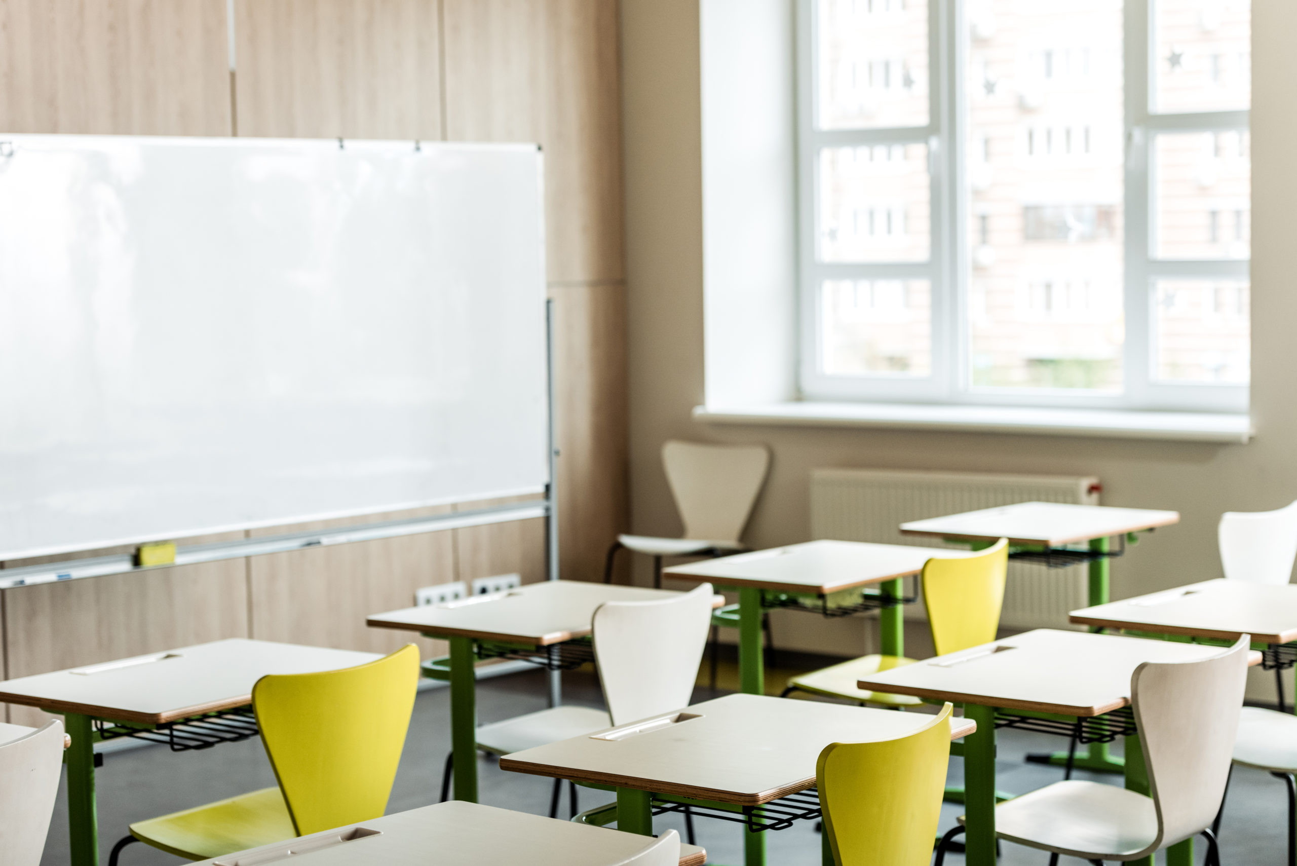 classroom with wooden desks, chairs, window and flipchart