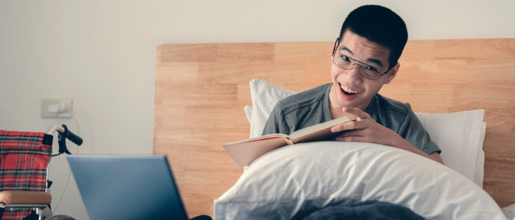 Teenager with disability reading with laptop