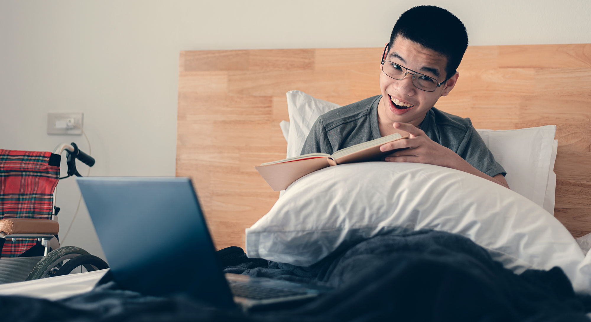 Teenager with disability reading with laptop